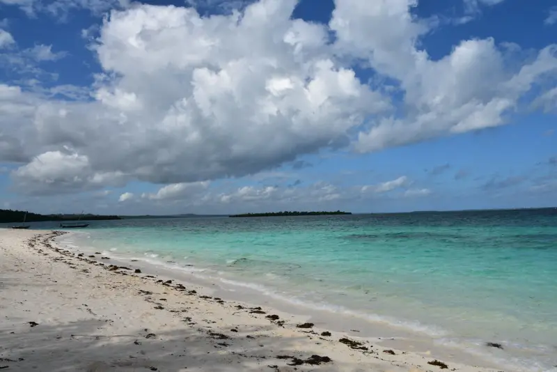 White sand and clear turquoise water under tall clouds at Nungwi, Zanzibar