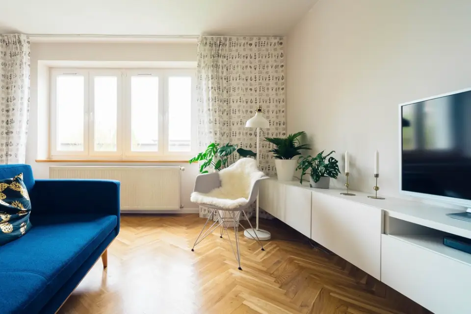 An apartment living room with a blue sofa and herringbone floor
