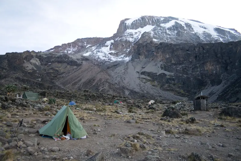 A lone tent below the snowy summit of Kilimanjaro