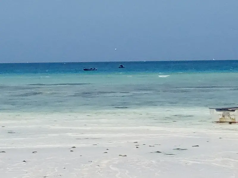 White sand and clear turquoise water at Nungwi, with boats moored offshore
