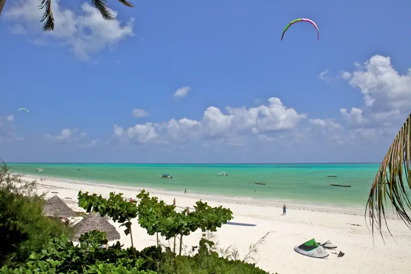 Palm-thatched huts behind a white beach and turquoise lagoon